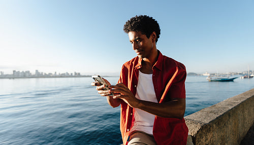 Brazilian man at Mureta Da Urca using smartphone by the water