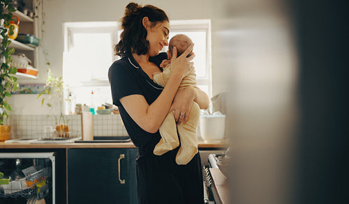 Mother embracing baby in cozy kitchen