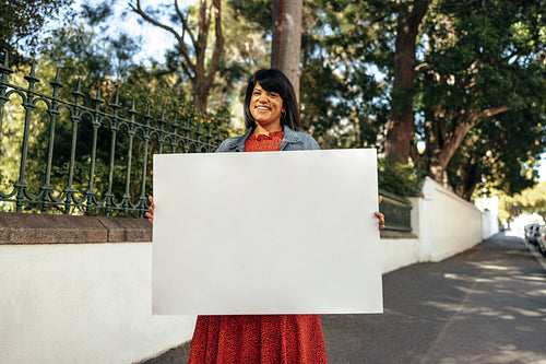 Carefree female activist displaying a blank banner outdoors
