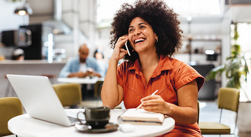 Happy business woman working in cafe, making appointments with her clients on a phone call