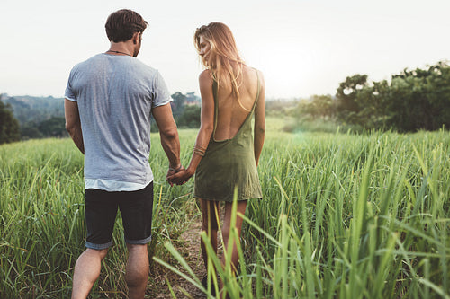 Young couple walking through grassy road