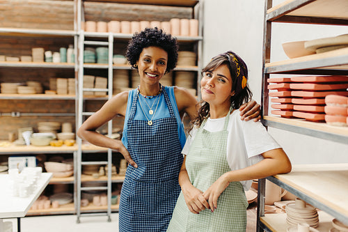 Happy young craftswomen smiling at the camera in their workshop