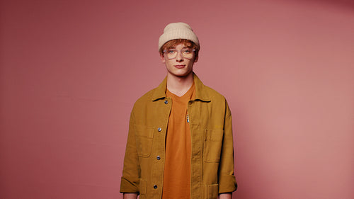 Stylish young man with glasses and a beanie posing for a studio portrait