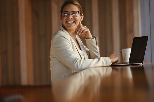 Happy business woman sitting in a coworking space with a laptop