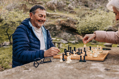 Happy senior couple playing chess in a park