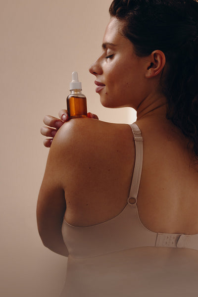 Woman holding amber glass bottle in mindful self-care ritual