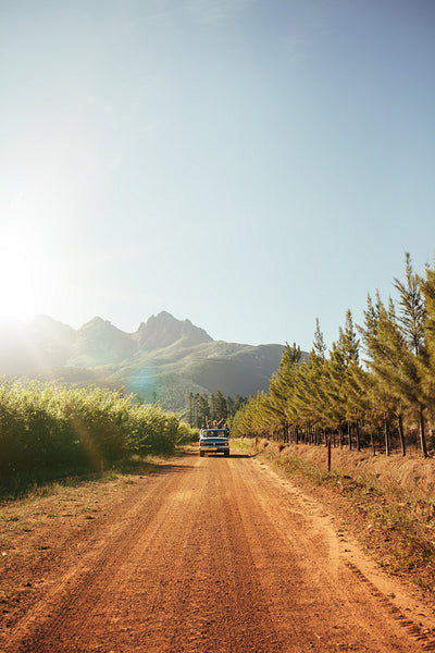 Distant car approaching on a rural dirt road on a sunny day