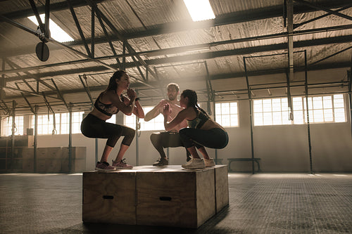 Fit young people doing box jumps in gym