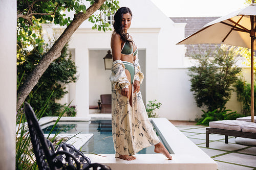 Carefree woman standing beside a pool in a bikini