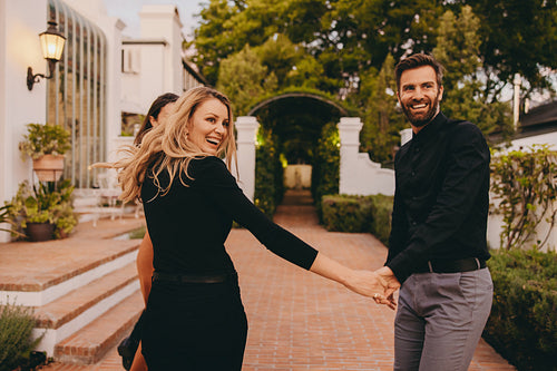 Smiling couple greeting their friends outside a hotel