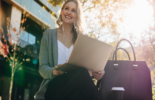 Woman sitting outdoors with a laptop