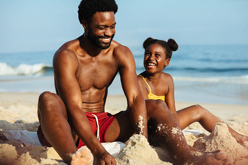 Father and daughter building sandcastles on a sunny beach vacation