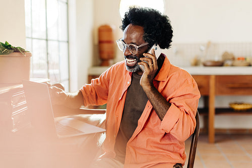 Happy mature man speaking on the phone in his home office
