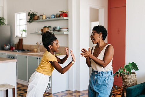 Cheerful mother and daughter enjoying a fun hand clapping game at home