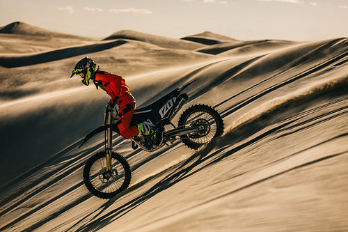 Professional motocross biker riding in sand dunes