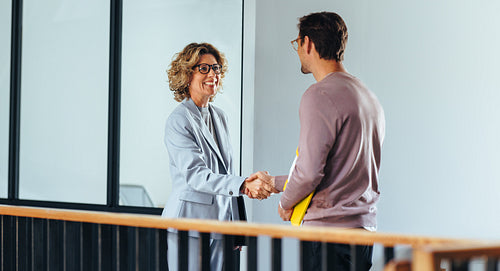 Hiring manager shaking hands with a job candidate in an office