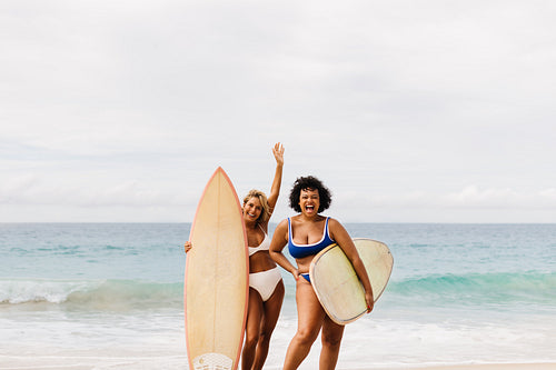 Female friends celebrating fun surfing day at the beach