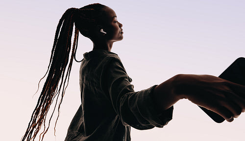 Young woman dancing with closed eyes, enjoying the flow of the music on her smartphone