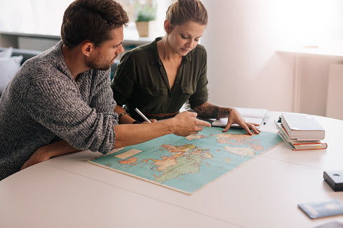 Young couple exploring the world map.