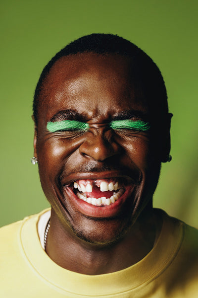 Laughing man portrait in the studio with bold makeup and a joyful expression
