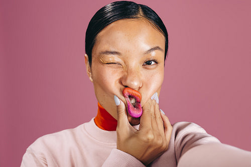 Taking a selfie with two toned lips, woman poses for the camera in a studio
