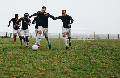 Group of men playing soccer on the field
