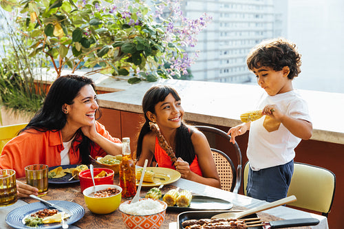 Latino family enjoying a meal together on a sunny outdoor terrace