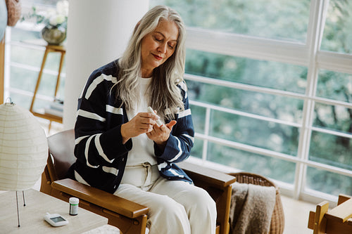 Senior woman tests blood glucose at home
