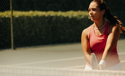 Female tennis player focused on the tennis court during a sunny outdoor match