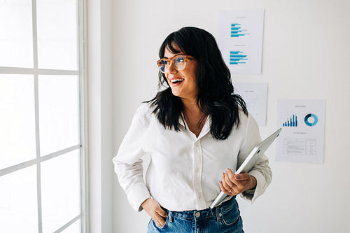 Female data analyst standing in an office and looking outside the window