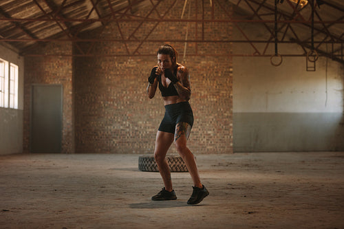 Woman shadow boxing in empty factory shade