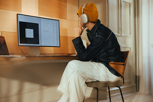 Focused work happens at a computer desk with headphones in a home office