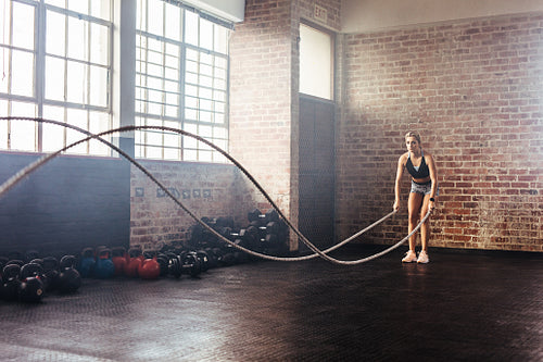 Athlete exercising in gymnasium using training ropes.