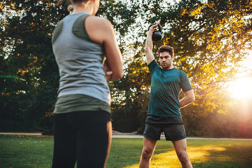 Young man doing weight training with trainer