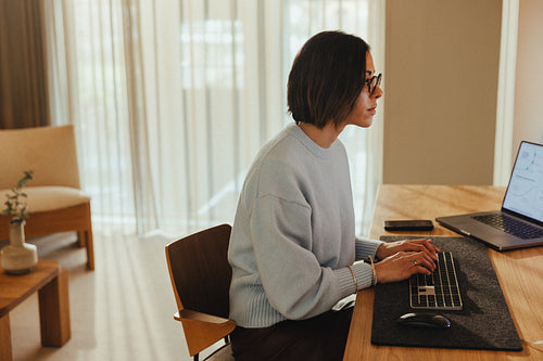 Woman works on a laptop at her desk in a warm office space
