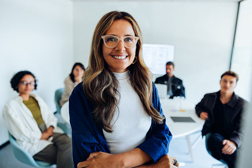 Business leader woman confidently posing with her team