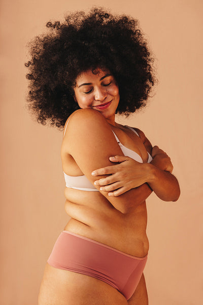 Body positive young woman embracing herself while wearing underwear