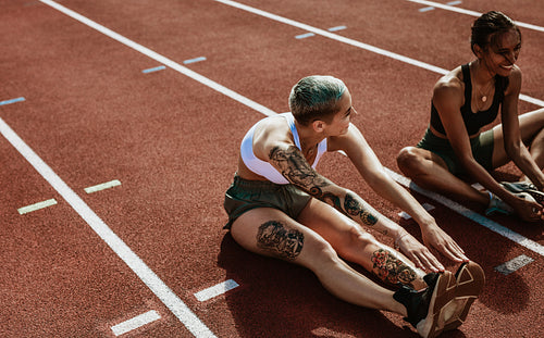 Athletes doing stretching exercises on running track