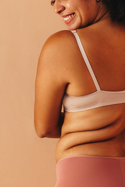 Back view of a happy plus size woman wearing underwear in a studio