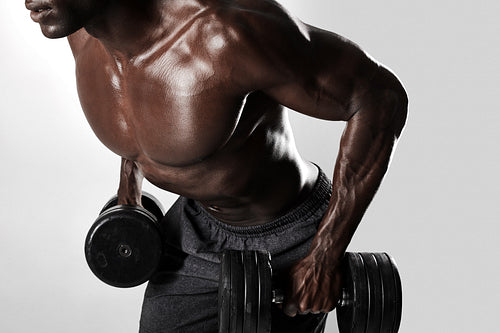 Fit young man exercising with dumbbells