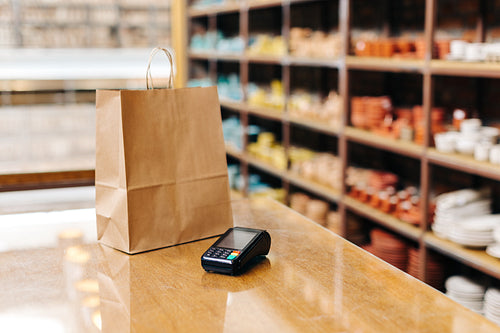 Still life shot of a shopping bag and a credit card machine on a table