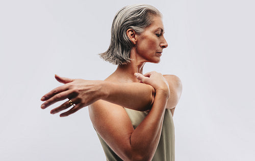Woman stretching arm across chest in studio