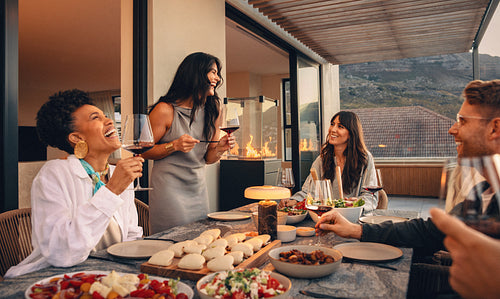 Friends enjoying a joyful dinner party with food and wine on a patio
