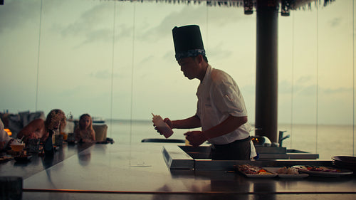 A captivating teppanyaki chef performs a stunning fire show for guests at a tropical resort