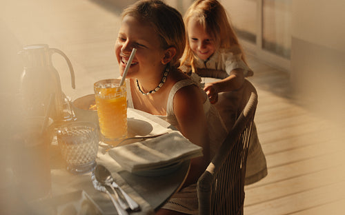 Happy girl enjoying orange smoothie outdoors at a villa