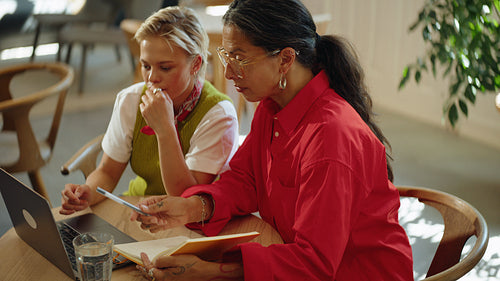 Seated women discuss business ideas over a laptop at a cafe table