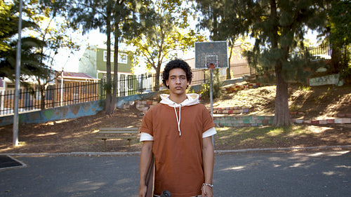 Teenage boy with skateboard standing outdoors
