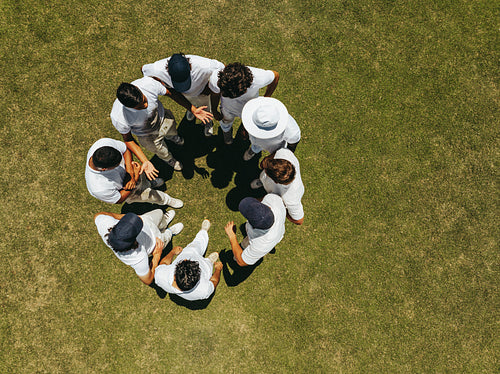 Team huddle on a sports field captured from above for a unity concept