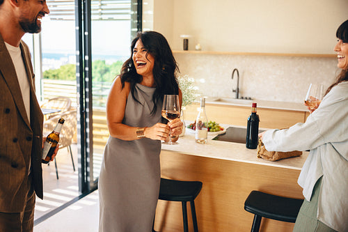 Friends sharing drinks and laughter in a stylish modern home