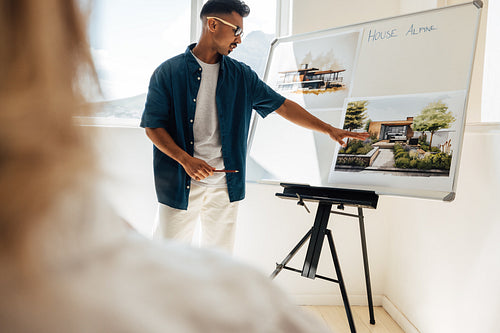 Architect presenting a modern house design on a whiteboard in a studio